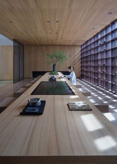 a person sitting at a long table in a room with wooden walls and flooring