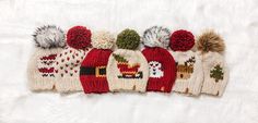 five knitted hats with pom - poms are lined up on a white surface