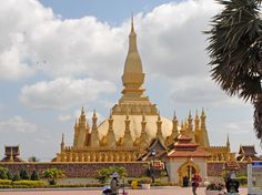 people are walking around in front of a large building with gold spires on it