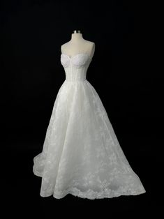 a white wedding dress on a mannequin headdress in front of a black background