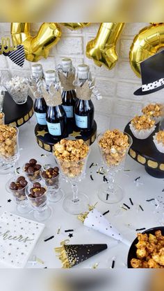 a table topped with lots of bottles of wine next to glasses filled with snacks and candies