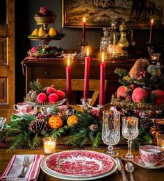 a dining room table set for christmas dinner with candles and fruit on the table top