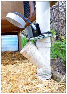 a water meter attached to the side of a building with straw in front of it