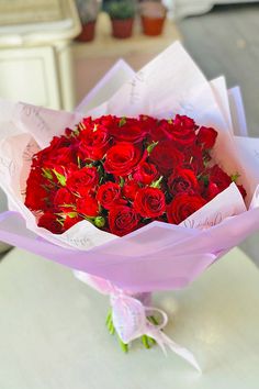 a bouquet of red roses sitting on top of a table