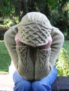 a person sitting on a bench with their back to the camera, wearing a sweater and hat