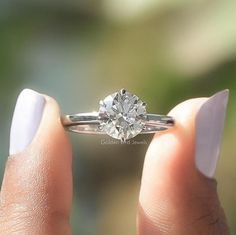 a woman's hand holding a diamond ring