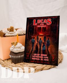 a cupcake next to a dvd cover on a wicker basket with an orange candle