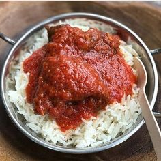 a bowl filled with rice and sauce on top of a wooden table