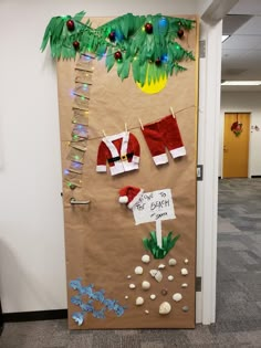 a bulletin board decorated with christmas stockings and santa clause hats on the door to an office cubicle