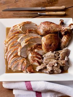 a white plate topped with sliced turkey and gravy on top of a wooden table