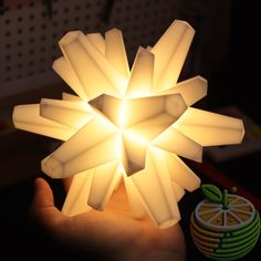 a hand holding a lit up paper snowflake