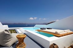 an outdoor lounge area overlooking the water and blue sky with wicker furniture on it