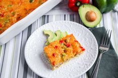 a white plate topped with a piece of food next to an avocado and tomato