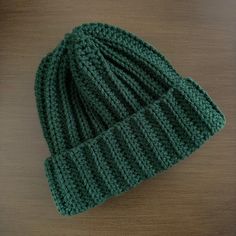 a green knitted hat sitting on top of a wooden table