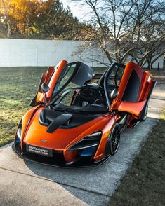 an orange and black sports car parked on the sidewalk