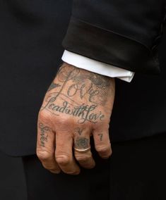 a man with tattoos on his arm and hand is wearing a black tuxedo