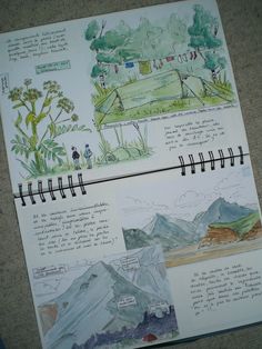 an open notebook with some drawings on the pages and in it is a drawing of mountains