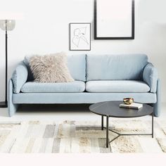 a blue couch sitting on top of a white rug next to a table and lamp