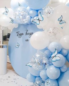 blue and white balloons with butterflies are on display in a room that is decorated for a baby's first birthday