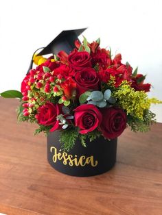 red roses and greenery in a black hatbox with the word fiesta written on it