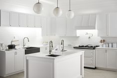 a kitchen with white cabinets and an island in the middle is lit by three hanging lights