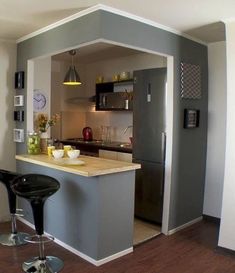 a kitchen with an island and bar stools in the middle, next to a refrigerator