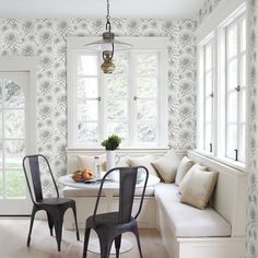 a dining room table with two chairs and a bench in front of the window next to it