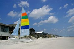 a sailboat on the beach in front of some houses