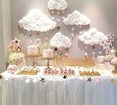 a table topped with lots of cakes and desserts next to clouds in the sky