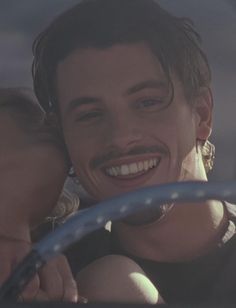 a man and woman are smiling while in a car