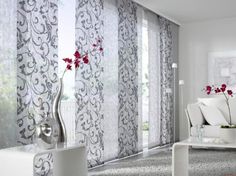 a living room filled with white furniture and red flowers in vases on the coffee table