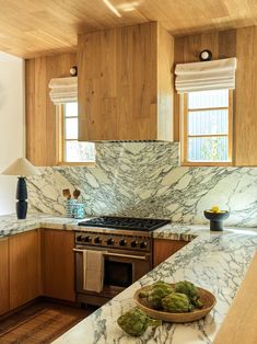 a kitchen with marble counter tops and wooden cabinets, along with a bowl of artichokes