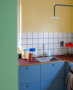 a kitchen with blue cabinets and yellow walls, an umbrella hanging from the ceiling over the sink