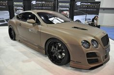 a tan car is on display at an auto show