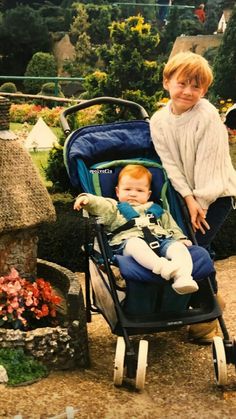 a young boy sitting in a stroller next to a woman with glasses on her face