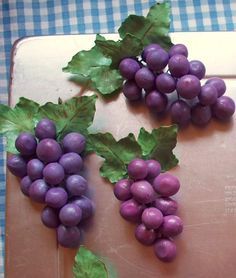 some grapes are laying on a cutting board with green leafy leaves attached to them