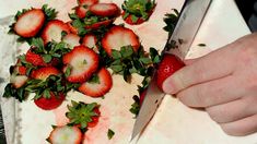 a person cutting strawberries with a large knife