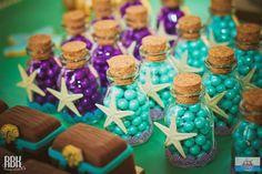 there are many small bottles filled with candy and starfish decorations on top of the table