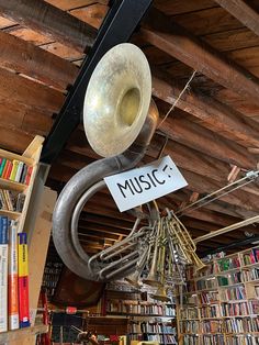 an old trumpet is hanging from the ceiling in a library with bookshelves full of books