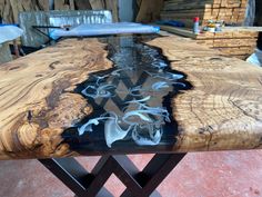 a table made out of wood and metal legs with glass top in the center, surrounded by stacks of wooden planks