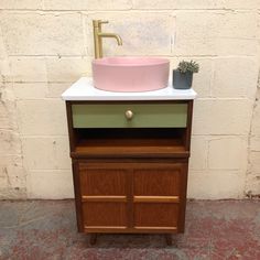 a bathroom sink sitting on top of a wooden cabinet next to a white brick wall