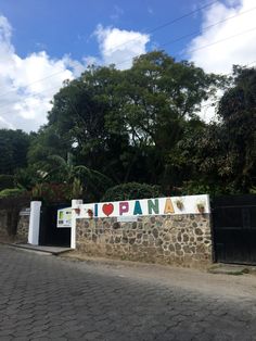 a sign that is on the side of a stone wall with trees in the background