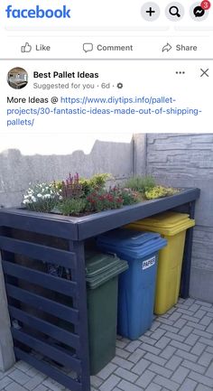 three trash cans sitting next to each other in front of a planter filled with flowers