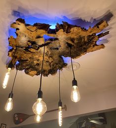 the light bulbs are on and there is a wood piece hanging from the ceiling above it