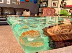 a glass table with seashells on it in the middle of a living room