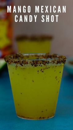 a cup filled with yellow liquid sitting on top of a blue table next to other cups