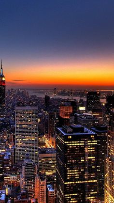 the city skyline is lit up at night, with skyscrapers in the foreground