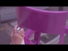 a woman is painting a purple chair with white paint on the bottom and side legs