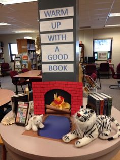 stuffed animals sit on a table in front of a sign that reads warm up with a good book