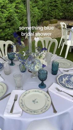 the table is set with blue and white plates, silverware, and vases